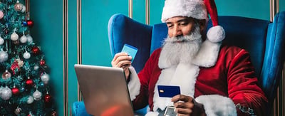 santa holding a credit card and using a laptop